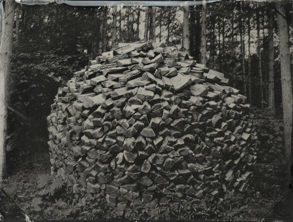 Nick Olsen's photography work uses 19th century methods. For example, this photo of a woodpile is actually an example of tintype photography, printed on a sheet of iron.